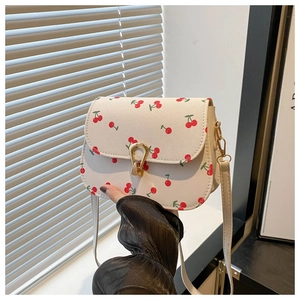 Détail du sac selle à fleurs avec imprimés cerises et boucle fer à cheval dorée chic