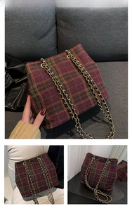 Close-up of red and green tartan woolen fabric and gold-tone woven chain strap of a tote bag
