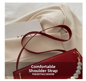 Detail of dark red leather handbag featuring elegant large white pearl beaded chain accent