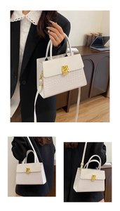 Detail of white crocodile pattern small handbag with gold buckle and adjustable strap
