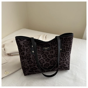 Detail of leopard print tote bag featuring black leather handles and gold rivet accents