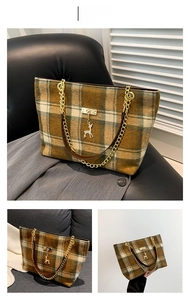 Detail of checkered tote bag featuring a gold deer charm and elegant chain strap