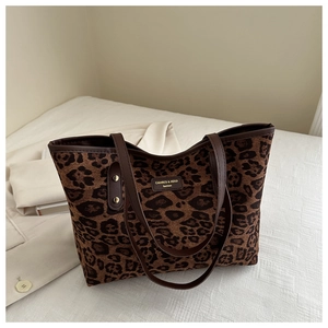 Macro detail of the leopard print fabric and golden rivet accents on the tote bag