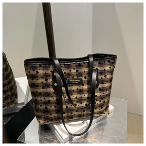 Detail of yellow plaid tote bag with black heart patterns and fashion brand plaque