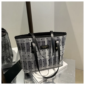 Detail of grid mesh tote bag with black strap and fashion label on a mirror surface
