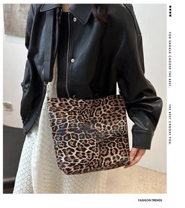 Close-up of leopard print canvas tote bag with black strap worn by a stylish model
