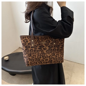 Detail of leopard print tote bag featuring a leather strap and luxury metal logo plaque
