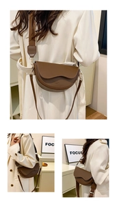 Vertical detail of a brown saddle crossbody bag with wide shoulder strap in minimalist setting