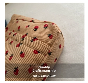 Close-up of beige corduroy fabric texture and cute red strawberry patterns on a tote bag