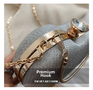 Detail showing the golden metal hook and sparkling silver sequin texture of the evening bag