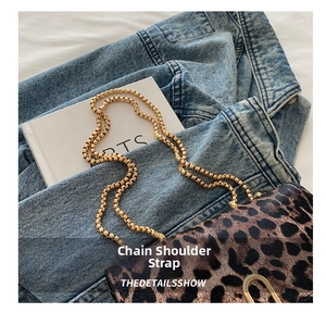 Close-up of leopard print crossbody bag featuring gold textured chain strap on denim fabric