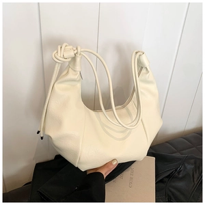 Detail of creamy white pleated hobo bag with knotted strap and soft leather texture