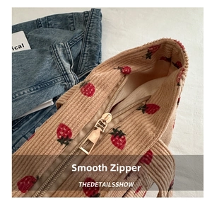 Detail of smooth metal zipper closure on corduroy tote bag with strawberry print