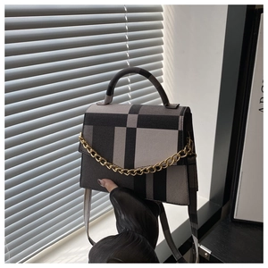 Detail of the gray and black checkered crossbody bag featuring a golden metal chain