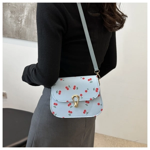 Détail du sac à bandoulière bleu clair avec imprimé cerise et fermoir doré