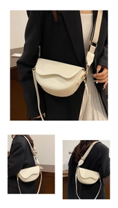 Detailed view of cream saddle bag featuring wavy flap design and wide fabric strap