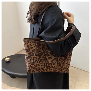Detail of trendy leopard print tote bag with brown leather straps and metal rivets