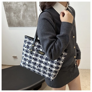 Detail showing blue and white checkered tote bag with black heart patterns and leather strap