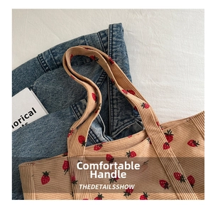 Detail of comfortable corduroy handle on beige tote bag with red strawberry print
