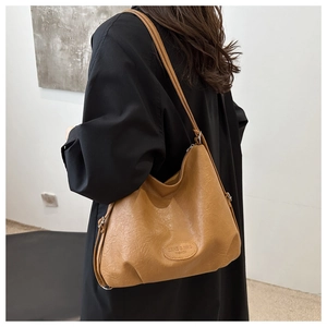 Detail of caramel tote bag showing vintage wrinkled texture and brand embossing