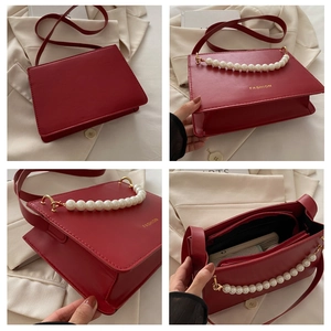 Detail showing the red square crossbody bag with pearl handle and inner zip pocket