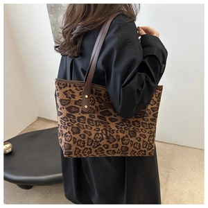 Detail of leopard print tote bag featuring brown leather straps and gold rivet accents