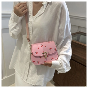 Détail du sac selle rose à imprimé cerise avec fermoir fer à cheval doré et texture en similicuir