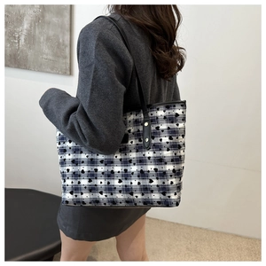 Detail of blue and white checkered tote bag with black heart patterns on model