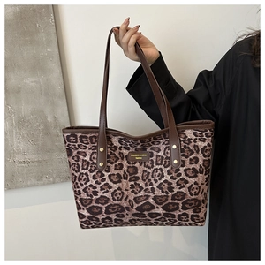 Detail of leopard print tote bag featuring a brand woven label and sturdy metal rivets