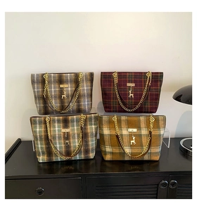 Close-up of four plaid wool tote bags featuring gold deer charms and chain handles