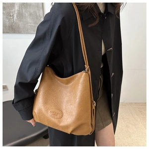 Detail of a brown Hobo tote bag showing textured soft leather and brand logo on the side