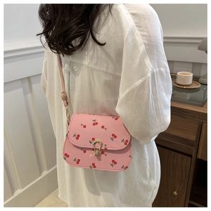 Détail du sac selle rose avec imprimés cerises et fermoir en métal doré