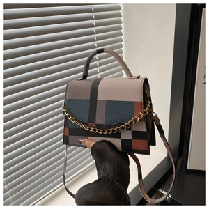 Detail view of a geometric color-block handbag with gold chain and crossbody strap
