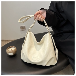 Detail of off-white hobo bag showing litchi texture and adjustable shoulder strap