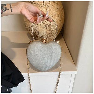 Detail of silver glitter heart clutch with gold circular handle and crystal clasp