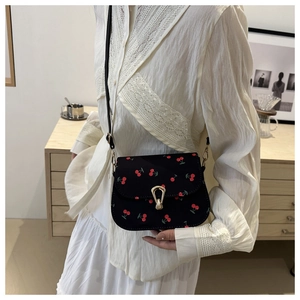 Détail du sac de selle noir avec imprimé cerises et boucle fer à cheval dorée