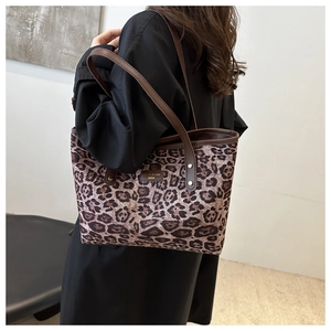 Detail of leopard print tote bag with brown leather handles and gold metal logo