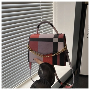 Detail of a plaid crossbody bag with bold gold chain and retro color-block pattern