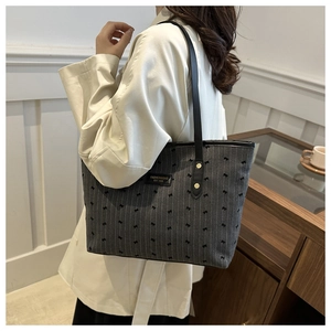 Detail of dark gray canvas tote bag with bow embroidery and black leather handles