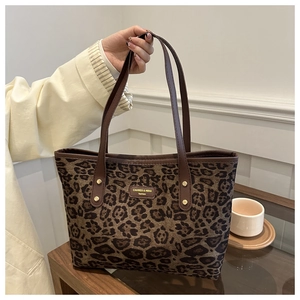 Close-up of leopard print tote bag featuring a leather strap and branded fashion logo