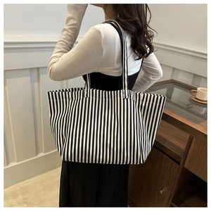Grand sac cabas en toile à rayures noires et blanches porté par un mannequin chic