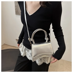 Silver crocodile pattern handbag with knot handles and curved base shown on model