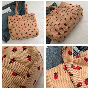 Detail of strawberry print corduroy tote bag showing textured fabric and wide handles