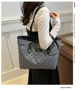 Détail du sac cabas gris à pois avec des anses en cuir noir et rivets dorés