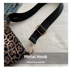 Detail of golden hardware hook and black strap on a leopard print crossbody bag