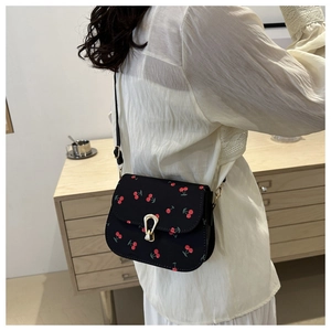 Vue détaillée du sac besace noir à motif cerises avec fermoir en métal doré