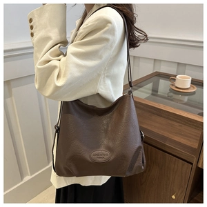 Detail of dark brown tote bag showing litchi grain texture and embossed leather brand tag