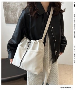 Detail of white drawstring shoulder bag with front pockets and soft leather texture
