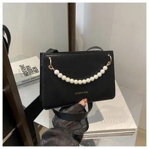 Detail of black leather square bag with large faux pearl handle and gold fashion logo