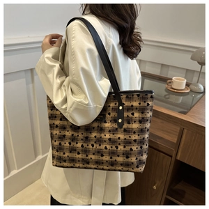 Detail of checkered tote bag showing heart prints and leather strap with gold studs